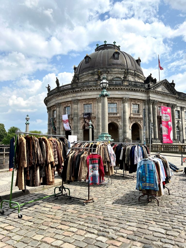 Street photography in Berlin. Photo of a clothing stand in a market. Colourful photo with old buildings in the background. m