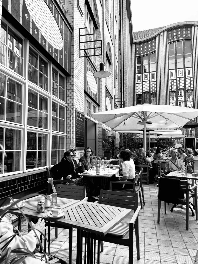 Street photography in Berlin. Photo of people eating in a cafe. Black and white photo. 